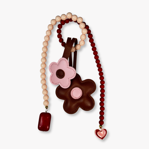 Bag charm with beads, a pink flower pendant, and a brown heart-shaped pendant on a white background