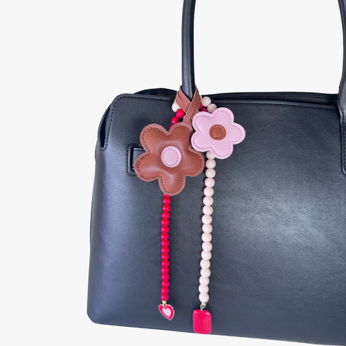 Decorative flower-shaped keychain with beads on a black handbag.