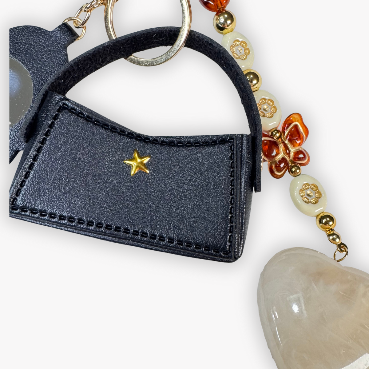 Black handbag-shaped keychain with a gold star on a white background