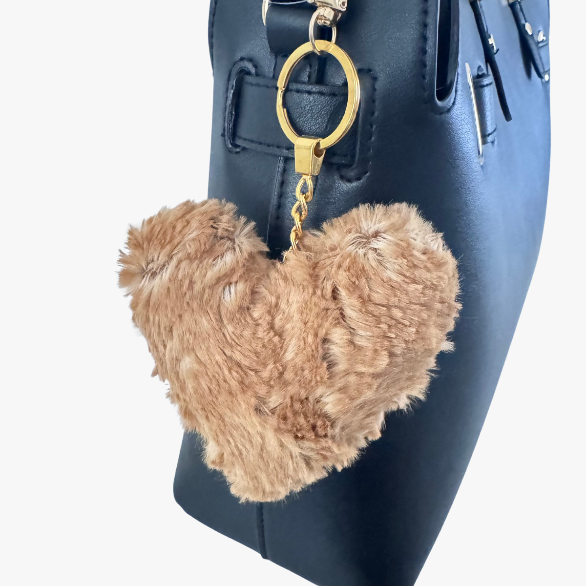 Heart-shaped fur keychain attached to a navy blue handbag.
