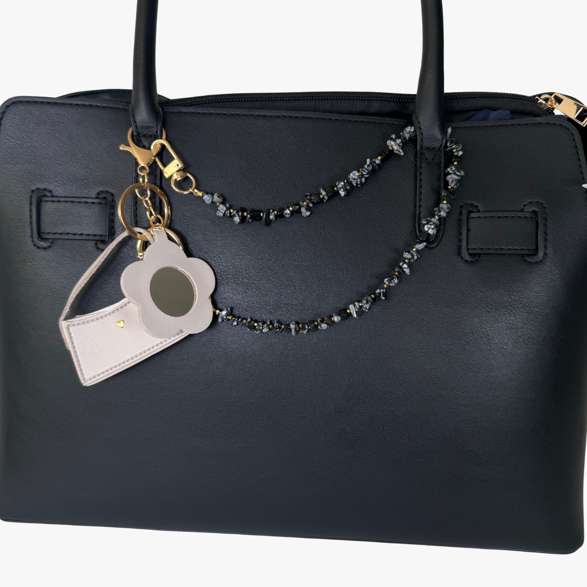 Black handbag with a decorative keychain on a white background