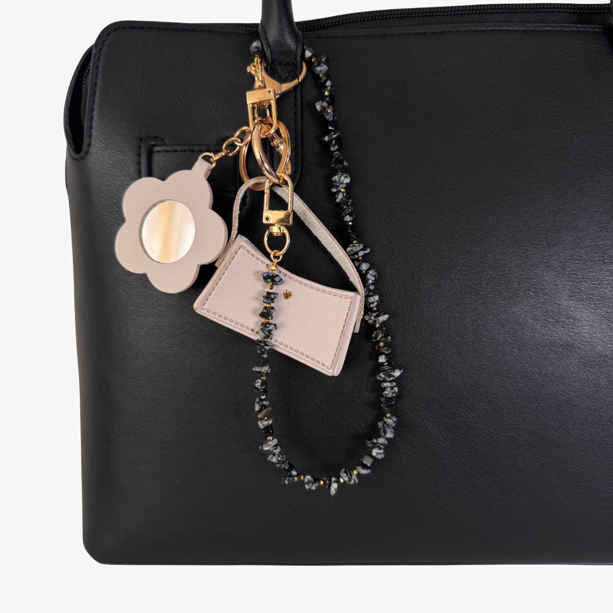 Black handbag with decorative keychain featuring a flower charm and beaded strap.