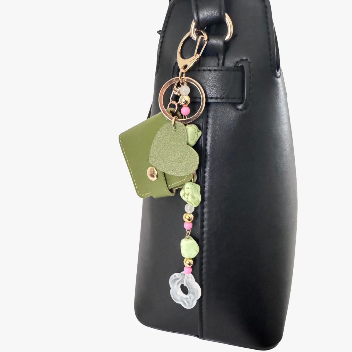 Black handbag with a decorative keychain featuring green leaves and pink beads on a white background
