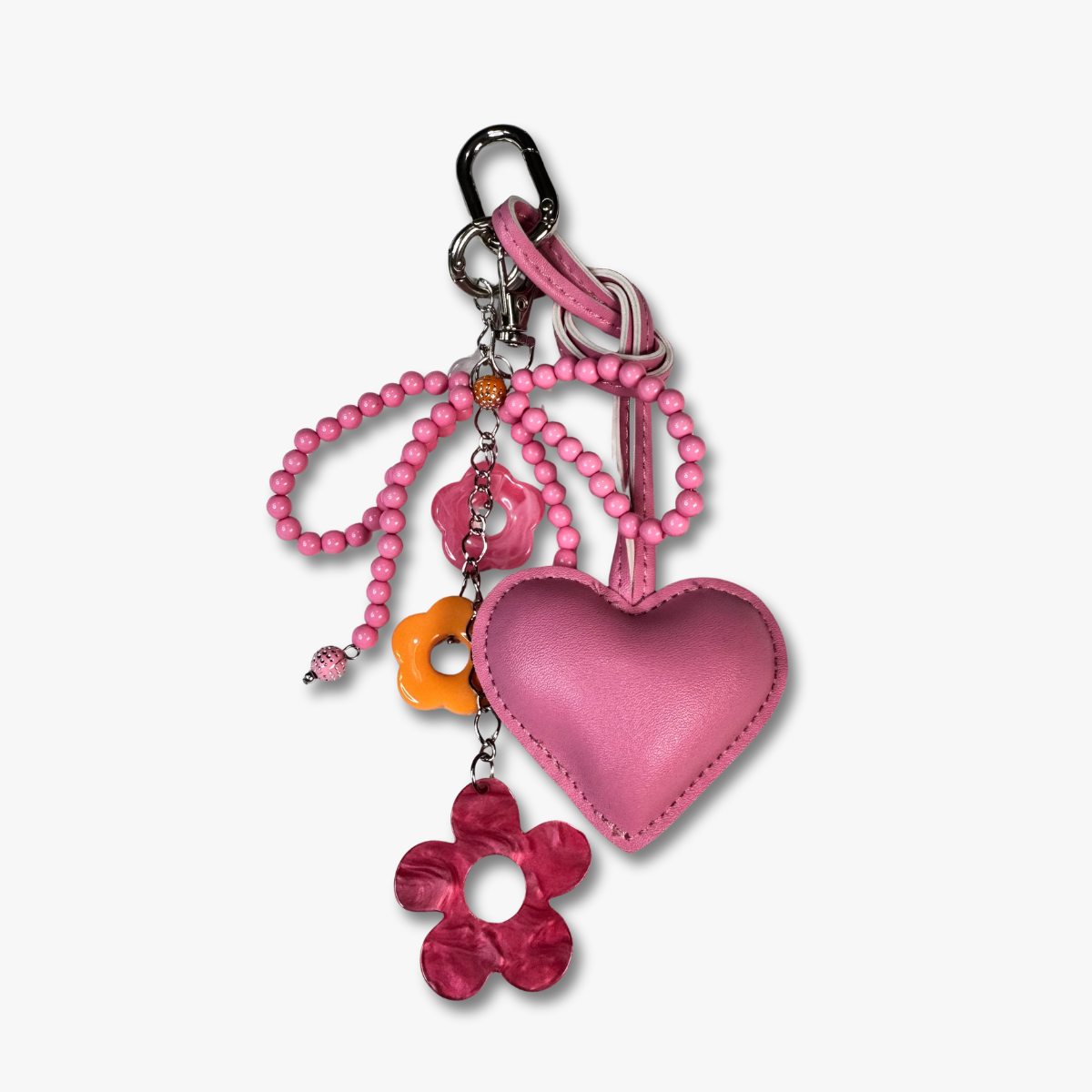 Pink heart-shaped keychain with beads and floral charm.